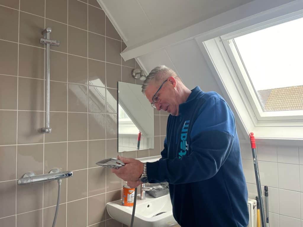 Fixer van het Fixteam die een waterbesparende douchekop installeert