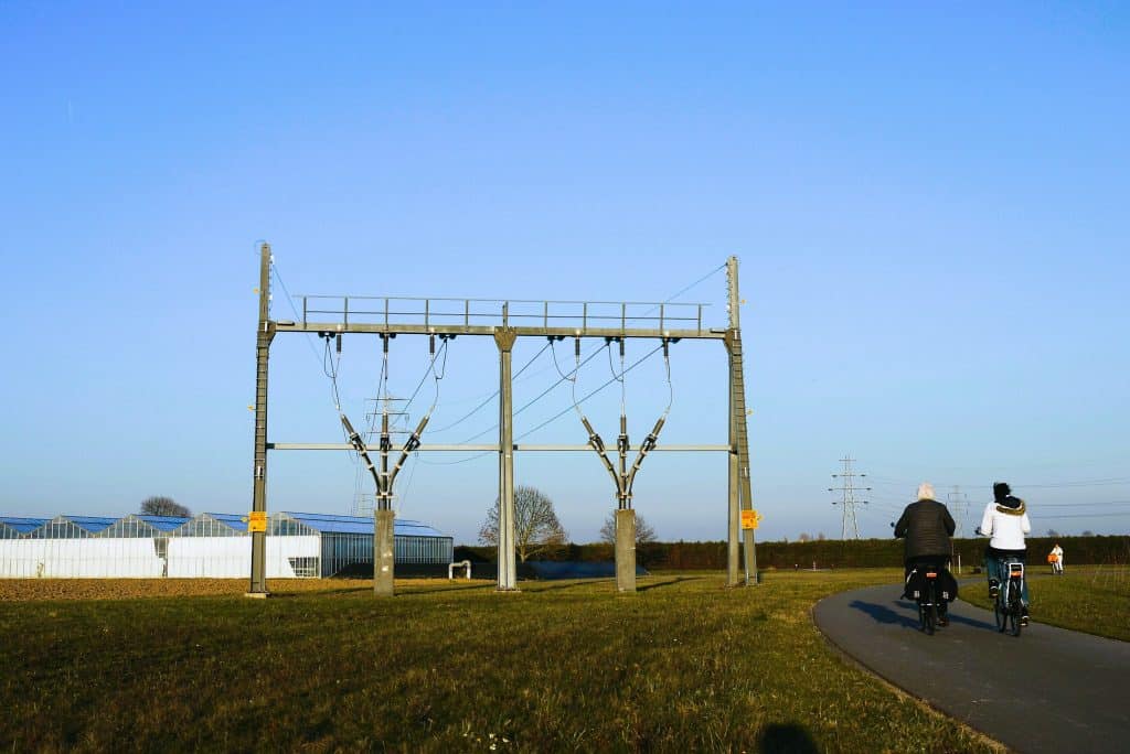 Hoogspanningskabels met twee mensen op de fiets